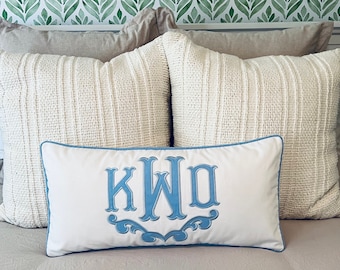 May include: Three white throw pillows with a white pillow with blue embroidered initials "KWO" in the center.