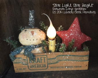 May include: A snowman lamp pattern in a wooden box with a red star and a light bulb. The box is labeled "KRAFT AMERICAN" and "PASTEURIZED PROCESS CHEESE". The text "Star Light, Star Bright" is written above the box. The text "(c) 2014 Liberty Creek Primitives" is written below the box.