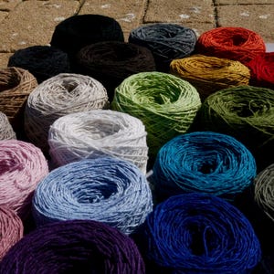 May include: A selection of colourful yarn skeins in shades of red, green, blue, and purple. The yarn is arranged in a close-up shot, highlighting the texture and vibrant hues of the fibre. Suitable for knitting and crochet projects.