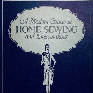 Op de afbeelding: Een vintage boekomslag met een blauwe achtergrond en een witte illustratie van een vrouw in een jurk. De titel van het boek is "A Modern Course in HOME SEWING and Dressmaking". Het boek is verdeeld in drie secties: Hemming, Closings, Facing, Buttonholes en Plackets.
