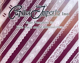 Pode incluir: Um folheto cor de vinho com o texto "Capitol Imports Inc." e "Your Passport to Fine Lace and Embroideries". O folheto apresenta um padrão de renda branca sobre um fundo cor de vinho. O texto "Order Department: 1-800-521-7647 1-800-433-5457 Fax: 1-850-386-3153 P.O. Box 13002 Tallahassee, FL 32317" está na parte inferior do folheto.