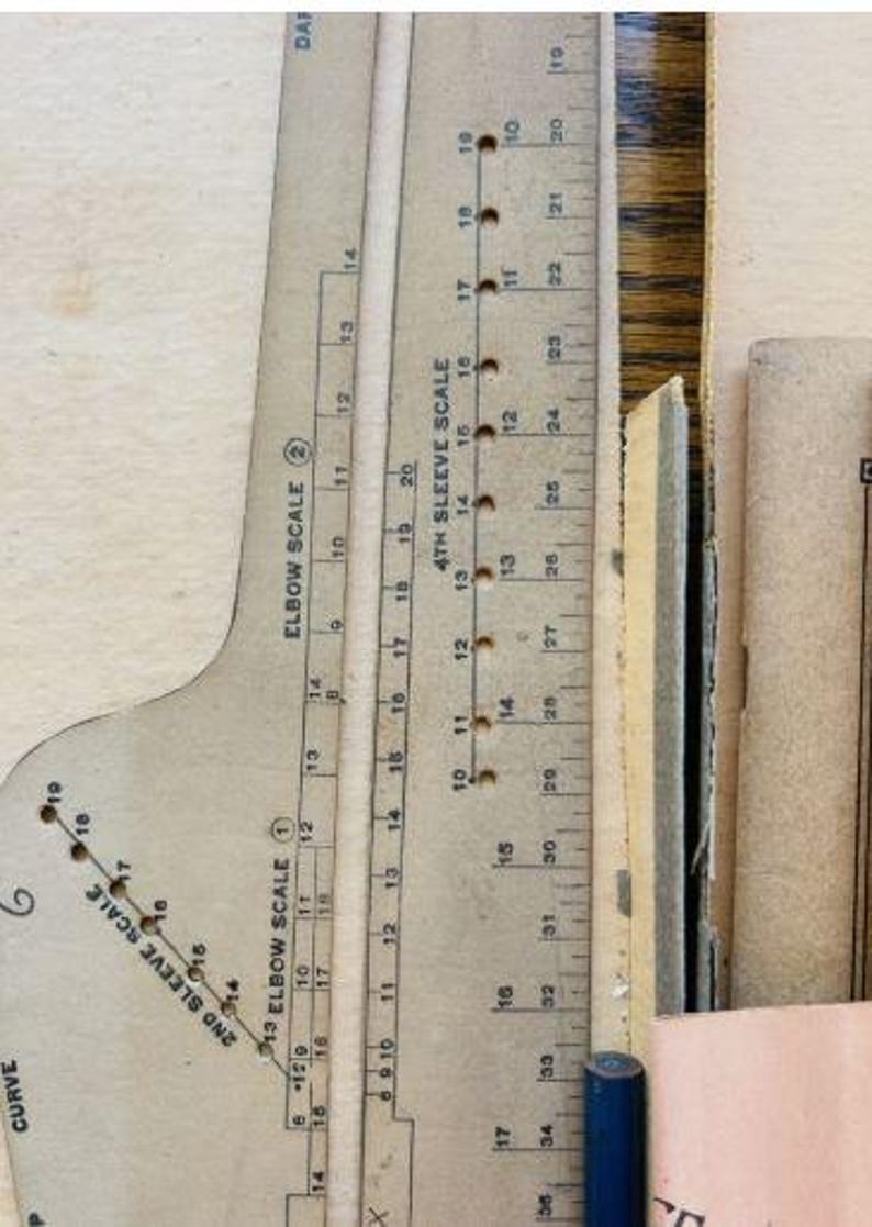 May include: A beige cardboard sewing pattern drafting tool featuring printed scales labeled Elbow Scale 2, 2nd Sleeve Scale, and 4th Sleeve Scale. The tool includes numerical markings and small circular holes for precise measurements in inches.