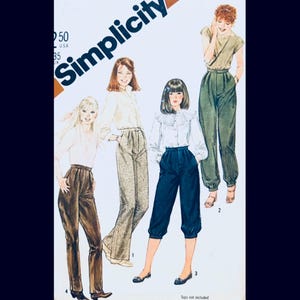May include: Simplicity sewing pattern featuring illustrations of women's pants in various styles. The pattern includes designs for high-waisted, pleated pants in brown, beige, and navy blue. The image has the Simplicity logo and the text "Tops not included".