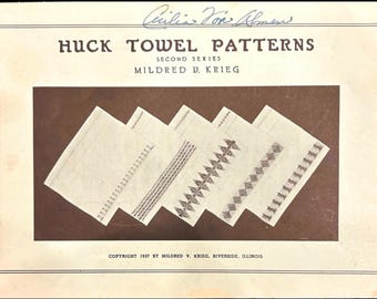 May include: A vintage booklet titled "Huck Towel Patterns, Second Series" by Mildred V. Krieg. The cover features a brown background with five white towels showcasing different embroidery patterns.