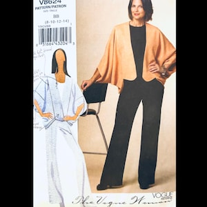 May include: A woman wearing a peach-colored cape-like jacket over a black top and black pants. The image also shows a pattern envelope with the text "V8624" and "The Vogue Woman" printed on it.