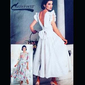 May include: A vintage sewing pattern featuring two dresses. The first dress is a floral print with 3/4 sleeves. The second dress is white with a low back and a bow at the waist. The pattern is from the Connoisseur Collection.