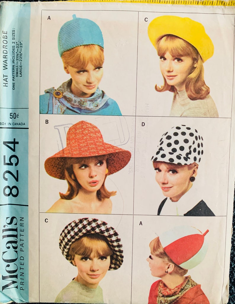 May include: A vintage sewing pattern for a hat wardrobe. The pattern includes instructions for making five different hats: a blue cloche hat, a yellow beret, a red and white sun hat, a black and white polka dot hat, and a red, white, and green hat. The pattern is for sizes small and large.