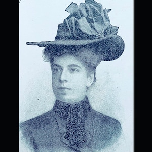 May include: A woman wearing a large, dark blue hat with a ruffled crown and a dark blue jacket.