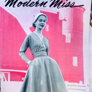 May include: Vintage magazine cover featuring a woman in a gray dress and hat, set against a pink background with a building silhouette. The magazine title "Modern Miss" is displayed in cursive. Text at the bottom reads "the fashion magazine for home economists and their students Spring 1953."