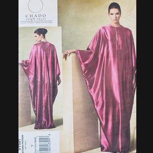 May include: A magenta-coloured dressmaking pattern for a long, flowing dress with wide sleeves. The pattern is labelled "V1181" and features the names "CHADO" and "ralph rucci" with the text "VOGUE PATTERNS AMERICAN DESIGNER".