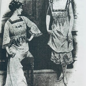May include: Black and white photo of two women wearing nightgowns. The woman on the left is sitting on a chair and the woman on the right is standing. The caption below the image reads "Fig. 100. Nightdress, Chemise and Drawers, 1911."