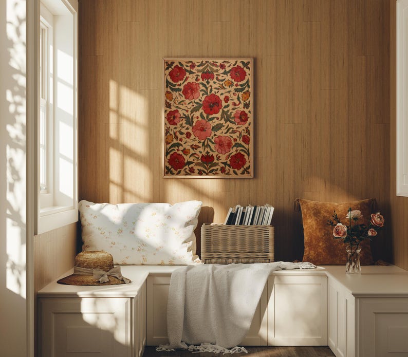 May include: A cozy interior scene featuring a framed floral artwork with red and pink blooms. A straw hat, pillows, and a woven basket are on a built-in bench. A soft blanket and a vase of roses add warmth.