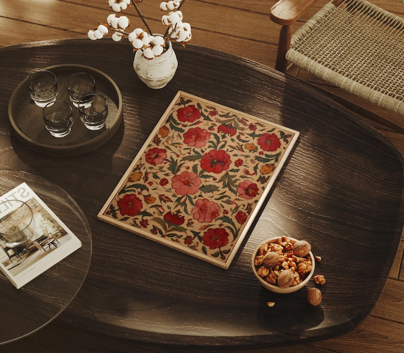 May include: A wooden coffee table with a floral patterned tray, a small bowl of nuts, and a tray of glasses. A vase with white flowers sits on the table. The tray features red and pink flowers.