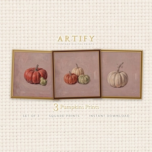 Può includere: Un set di tre stampe digitali quadrate intitolate ARTIFY VINTAGE DIGITAL PRINTS e 3 Pumpkins Prints. Ogni stampa presenta dipinti a olio di zucche in tonalità arancione, verde e crema su uno sfondo color malva tenue.