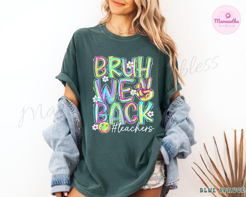 K&ouml;nnte beinhalten: Dunkelgr&uuml;nes T-Shirt mit dem Text "BRUH WE BACK" in bunten, umrandeten Buchstaben. Das Design beinhaltet ein Friedenszeichen, Blumen und ein Smiley-Gesicht, mit dem Hashtag "#teachers" darunter. Das Shirt hat kurze &Auml;rmel.