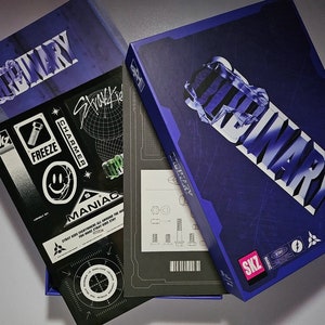 May include: A blue box with the word "Ordinary" printed in white on the front. The box is open and contains a black and white sticker sheet with various designs, including a smiley face, a screw, and the word "Maniac". The box also contains a black and white sheet with a barcode and a diagram of screws.