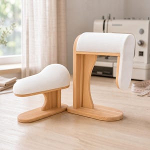 Könnte beinhalten: Zwei Schneiderpuppen aus Holz mit weißen, gepolsterten Oberflächen. Die Bretter sind aus hellem Holz gefertigt und dienen zum Bügeln von gebogenen Nähten und Ärmeln. Ein Brett ist horizontal, das andere vertikal.