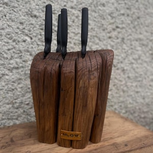 May include: A wooden knife block with four black handled knives. The block is made of reclaimed wood and has a rustic look. The block is labelled "NLOW" on the bottom.