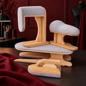 May include: A set of four wooden tailoring tools for pressing garments, including a sleeve board, a tailor's ham, a clapper, and a point presser. Each tool features light-toned wood construction with padded, heather gray fabric surfaces.