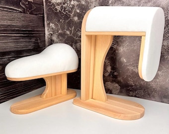 May include: Two wooden pressing tools with light-colored natural wood bases and vertical supports. Each tool features a smooth, curved top section padded with white fabric, designed for pressing curved seams and garment shapes during sewing projects.