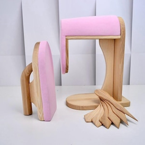 Op de afbeelding: Houten onderdelen van een paspop met roze accenten. De set bevat een strijkijzervormig stuk, een standaard met een roze gewatteerde bovenkant en diverse houten gereedschappen. De items zijn gemaakt van lichtgekleurd hout.