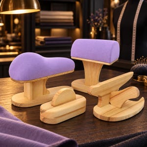 May include: A set of four sewing tools including two lavender fabric-covered pressing hams with light wood bases, one rectangular wooden clapper with a handle, and one wooden point presser with a base, all arranged for garment tailoring.