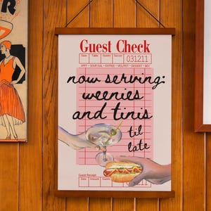 May include: A pink and white guest check with the text "now serving: weenies and tinis til late" in black cursive writing. The check has a red border and a red line down the center. There is a drawing of a hand holding a martini glass and another hand holding a hot dog.