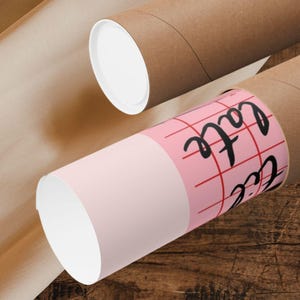 May include: A pink and white mailing tube with a red grid pattern and the text "Cafe" written in black. The tube is partially inside a brown mailing tube.
