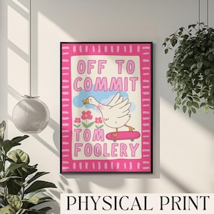 May include: A framed print featuring a cartoon goose on a skateboard, with the words "OFF TO COMMIT TOM FOOLERY". The print has a pink border and is labeled "PHYSICAL PRINT". The artwork is set against a cream background.