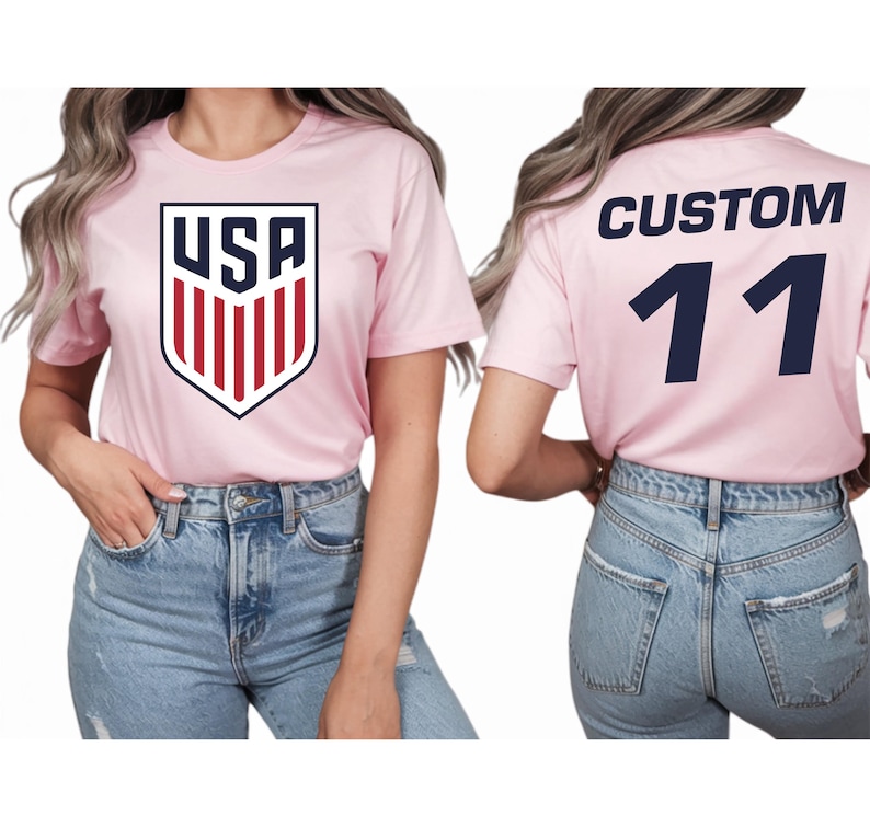 A woman wearing a pink t-shirt with the USA logo and the number 11 on the back, paired with blue jeans.