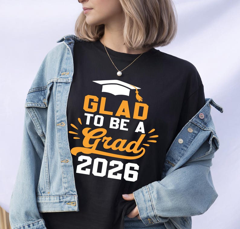 A person wearing a black t-shirt with the text "GLAD TO BE A GRAD 2026" printed on it, along with a graduation cap graphic.