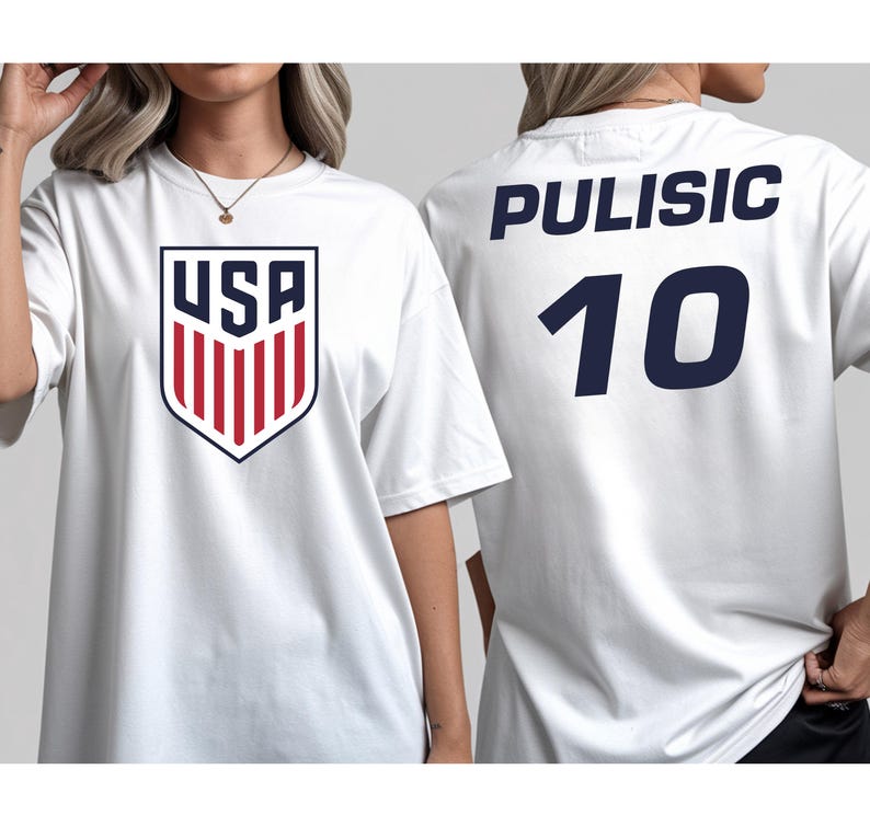 A white t-shirt with a red and blue shield-shaped logo and the name 'PULISIC' printed on the back, along with the number '10'.