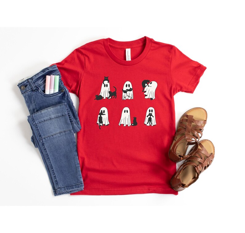 a red shirt with ghost faces on it next to a pair of jeans