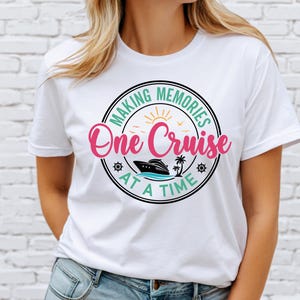 May include: White t-shirt with a circular graphic that reads "MAKING MEMORIES One Cruise AT A TIME." The design includes a cruise ship, palm tree, and sun. The text is in pink, black, and green.