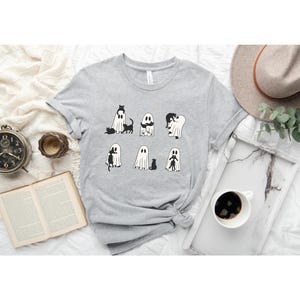 a t - shirt with ghost faces on it next to a cup of coffee