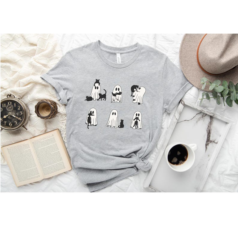a t - shirt with ghost faces on it next to a cup of coffee