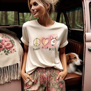May include: Cream-colored t-shirt with rolled sleeves featuring a peace sign, heart, and dog illustration with the words "Peace Love Dogs." The shirt is paired with floral print pants. A dog is visible in the background.