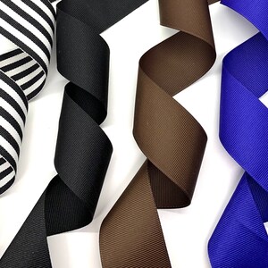 May include: Four different ribbon rolls in black and white stripes, black, brown, and blue. The ribbons are all 1 inch wide and are made of a soft, silky material.