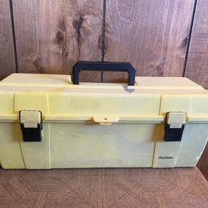 May include: A yellow plastic tool box with a black handle and latches. The box is rectangular and has a slightly worn appearance. The brand name "Real Value" is printed on the side.