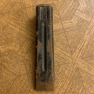 May include: A black metal wedge with a rectangular shape and a tapered end. The wedge has a central groove and shows signs of rust. The text "MADE IN USA" and "DASCO 500" are visible on the top.