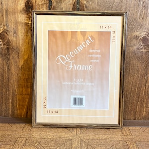May include: A rectangular document frame with a dark brown wood-grain finish. The insert displays the text Document Frame, diplomas, certificates, awards, 11 x 14, and vertical or horizontal display, along with a barcode and brand logo.