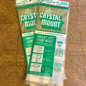 May include: Two packages of Crystal Mount stamp mounts. The packaging is green and gold with the words "Crystal Mount" in large white letters. The packaging also includes instructions and the words "World's Best Stamp Mount".