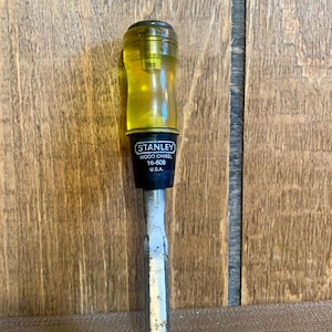 May include: A yellow and black Stanley wood chisel with the text "STANLEY WOOD CHISEL 16-608 U.S.A." on the handle.