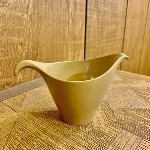 May include: A brown ceramic gravy boat with a curved handle.