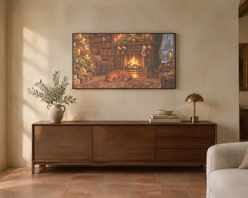 May include: A rectangular wall art print depicting a cozy living room scene with a fireplace, a decorated Christmas tree, and a dog sleeping on a rug. The artwork is displayed above a long, dark wood sideboard with three drawers and two doors.