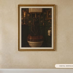 May include: A framed wall art print featuring a dark, moody bathroom scene with a black cat sitting on a wooden toilet seat. The room has dark green floral wallpaper, a lit candle on a stand, and a roll of toilet paper on a holder.