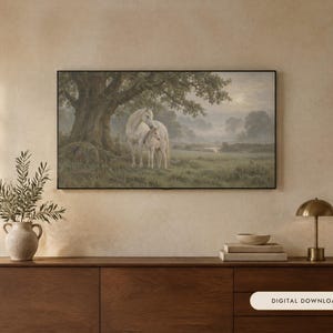 May include: A rectangular wall art print in a black frame depicting a white horse and foal standing under a large tree in a misty, green meadow. The artwork features a soft, muted color palette with a hazy sunlit sky in the background.