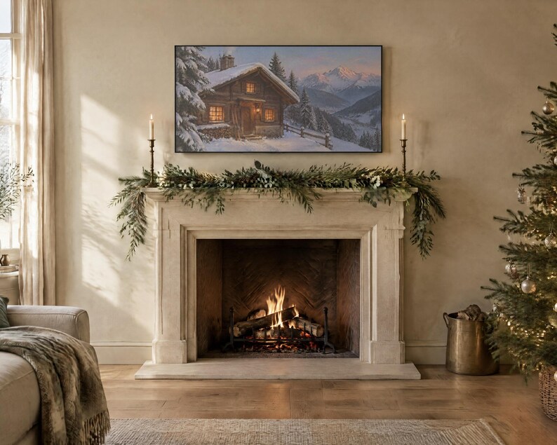 May include: A rectangular television screen mounted above a stone fireplace displays a winter landscape painting of a wooden cabin in the snow. The fireplace mantel is decorated with green pine garland and two tall, thin metal candle holders.
