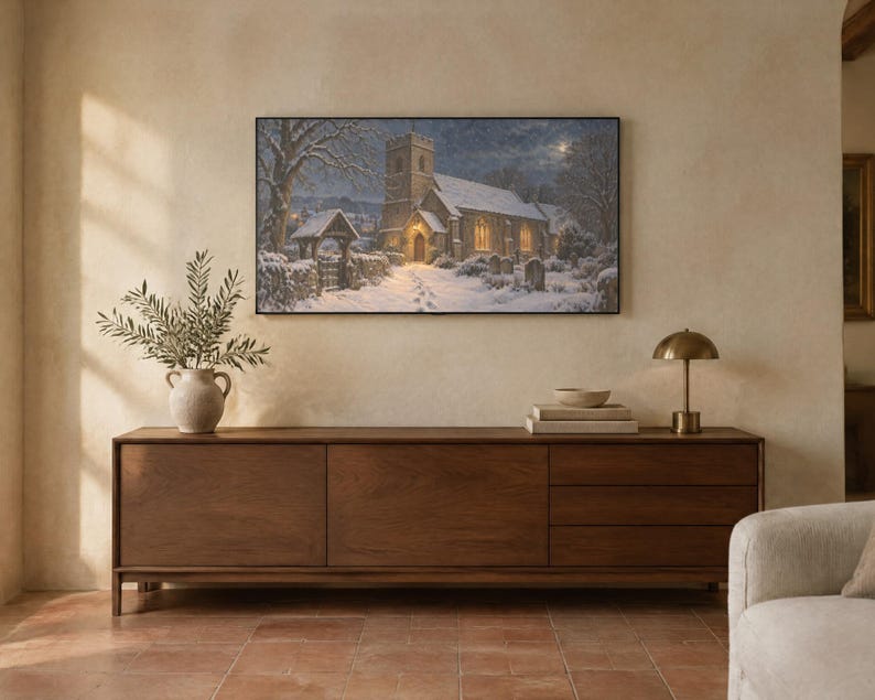 Puede incluir: Una impresi&oacute;n de arte mural rectangular que representa una iglesia de piedra en un paisaje invernal nevado por la noche, con ventanas de brillo c&aacute;lido, un camino cubierto de nieve y &aacute;rboles desnudos bajo un cielo iluminado por la luna, enmarcada en un borde negro fino.