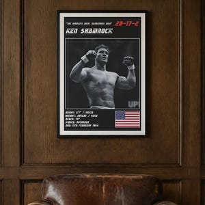 May include: A framed poster featuring a black and white photograph of Ken Shamrock with his arms raised. The text reads "The World's Most Dangerous Man" 28-17-2, Ken Shamrock, height 6'1" / 185cm, weight 205lbs / 93kg, reach 73", stance orthodox, DOB 11th February 1964, and a US flag.